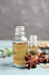 Photo of Anise essential oil and spice on light blue table