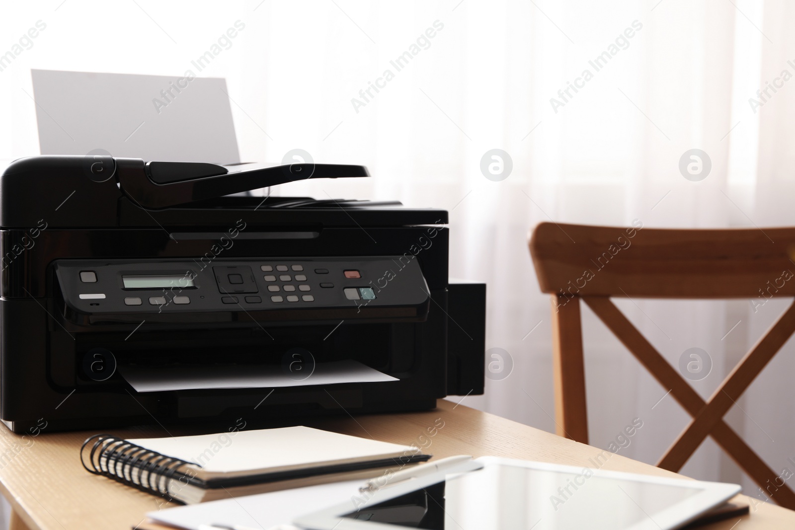 Photo of Modern printer, tablet and office supplies on wooden table indoors