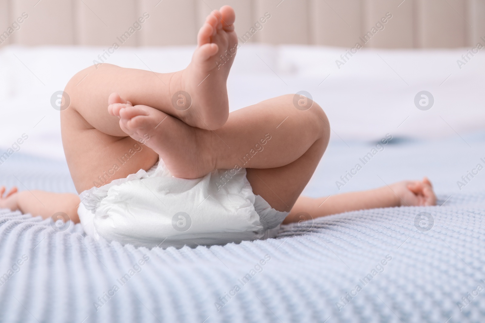 Photo of Little baby in diaper on bed, closeup