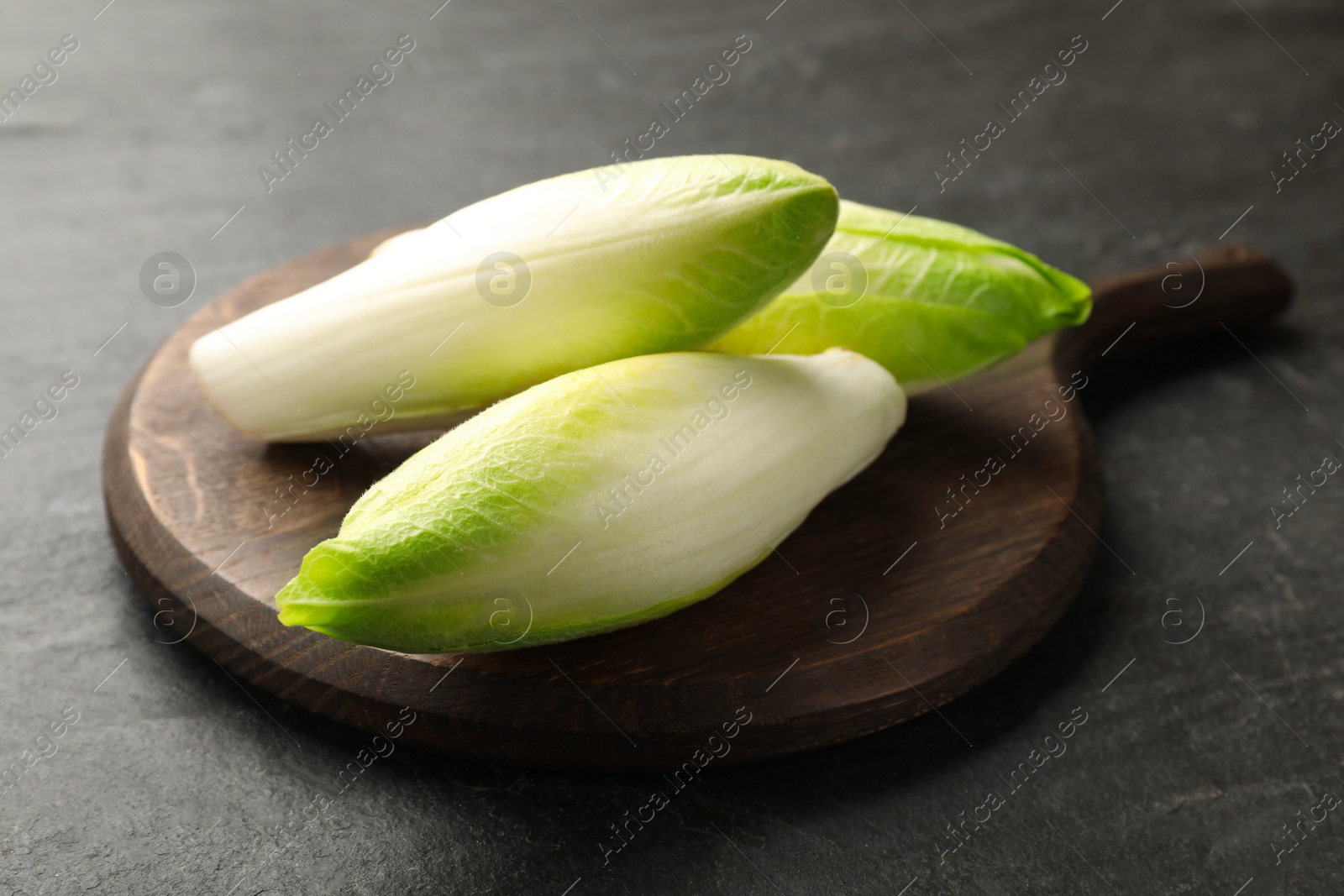 Photo of Fresh raw Belgian endives (chicory) on black table