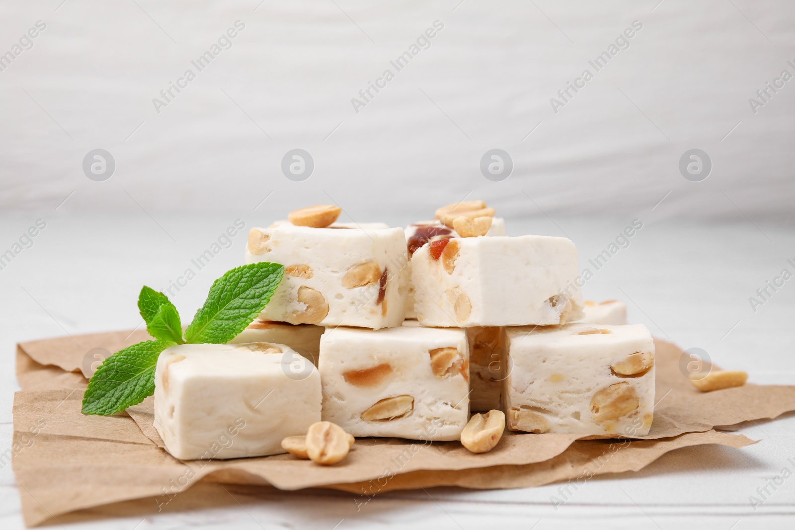 Photo of Pieces of delicious nutty nougat on parchment paper, closeup