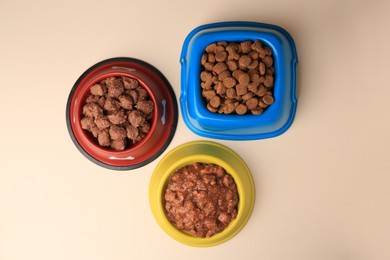 Dry and wet pet food in feeding bowls on beige background, flat lay