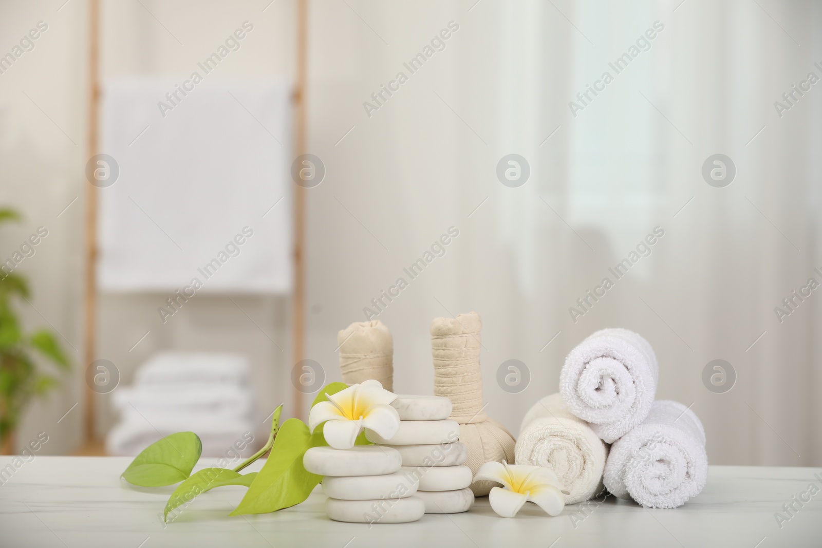 Photo of Composition with different spa products and plumeria flowers on white marble table indoors, space for text