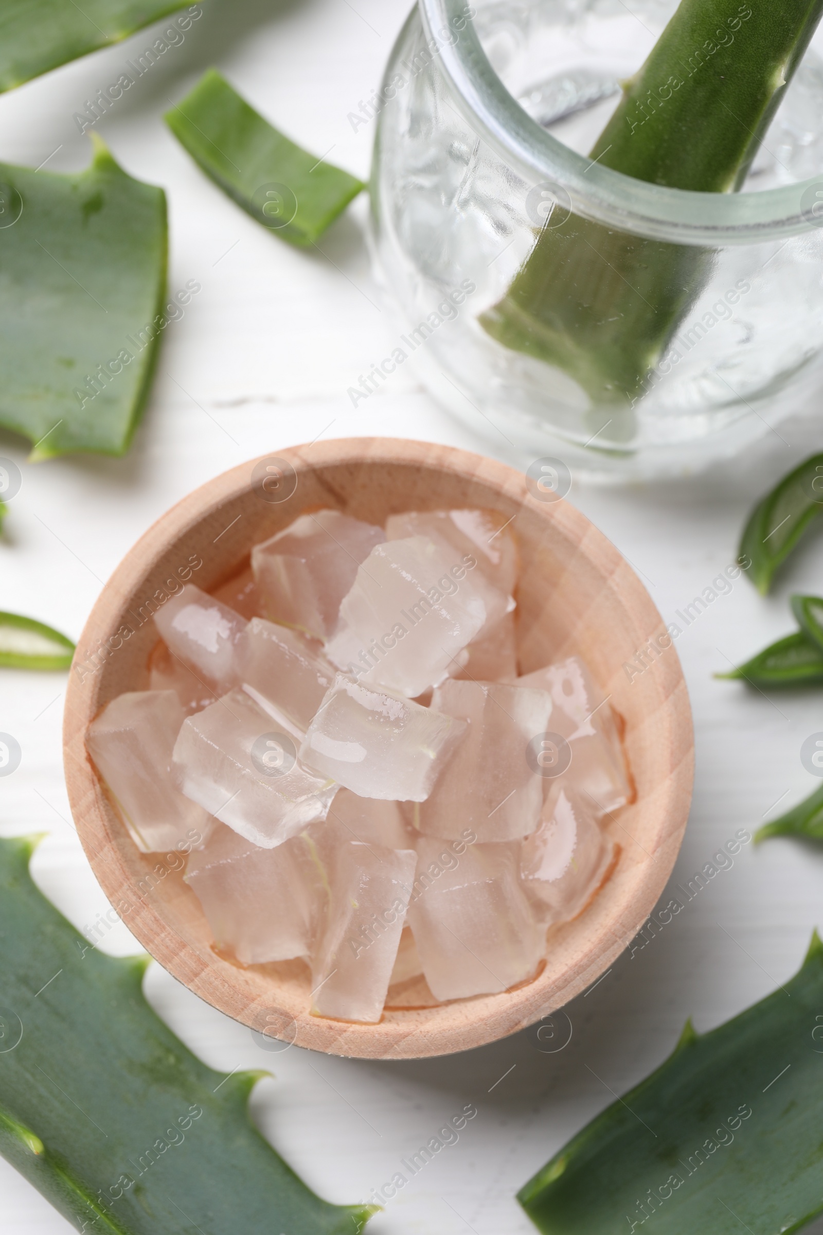 Photo of Aloe vera gel and slices of plant on white table, flat lay