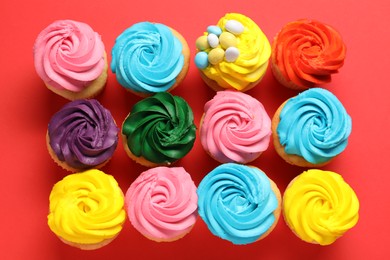 Delicious cupcakes with bright cream on red background, flat lay