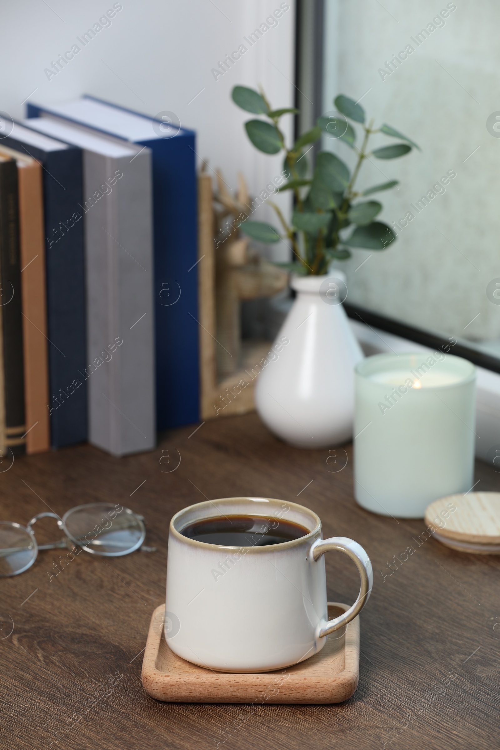 Photo of Cup of coffee with books and home decor on wooden window sill