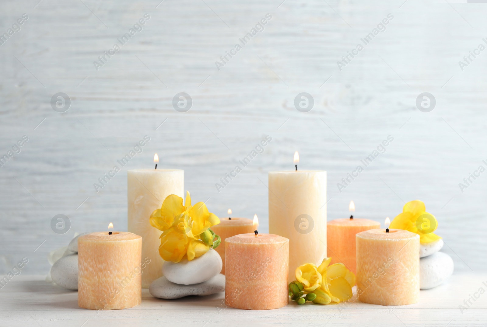 Photo of Composition of burning candles, spa stones and flowers on table. Space for text