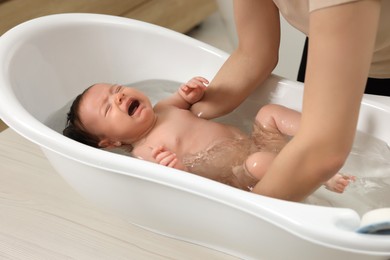 Photo of Mother bathing her little baby in bathtub, closeup