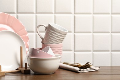 Photo of Beautiful ceramic dishware, cups and cutlery on wooden table, space for text