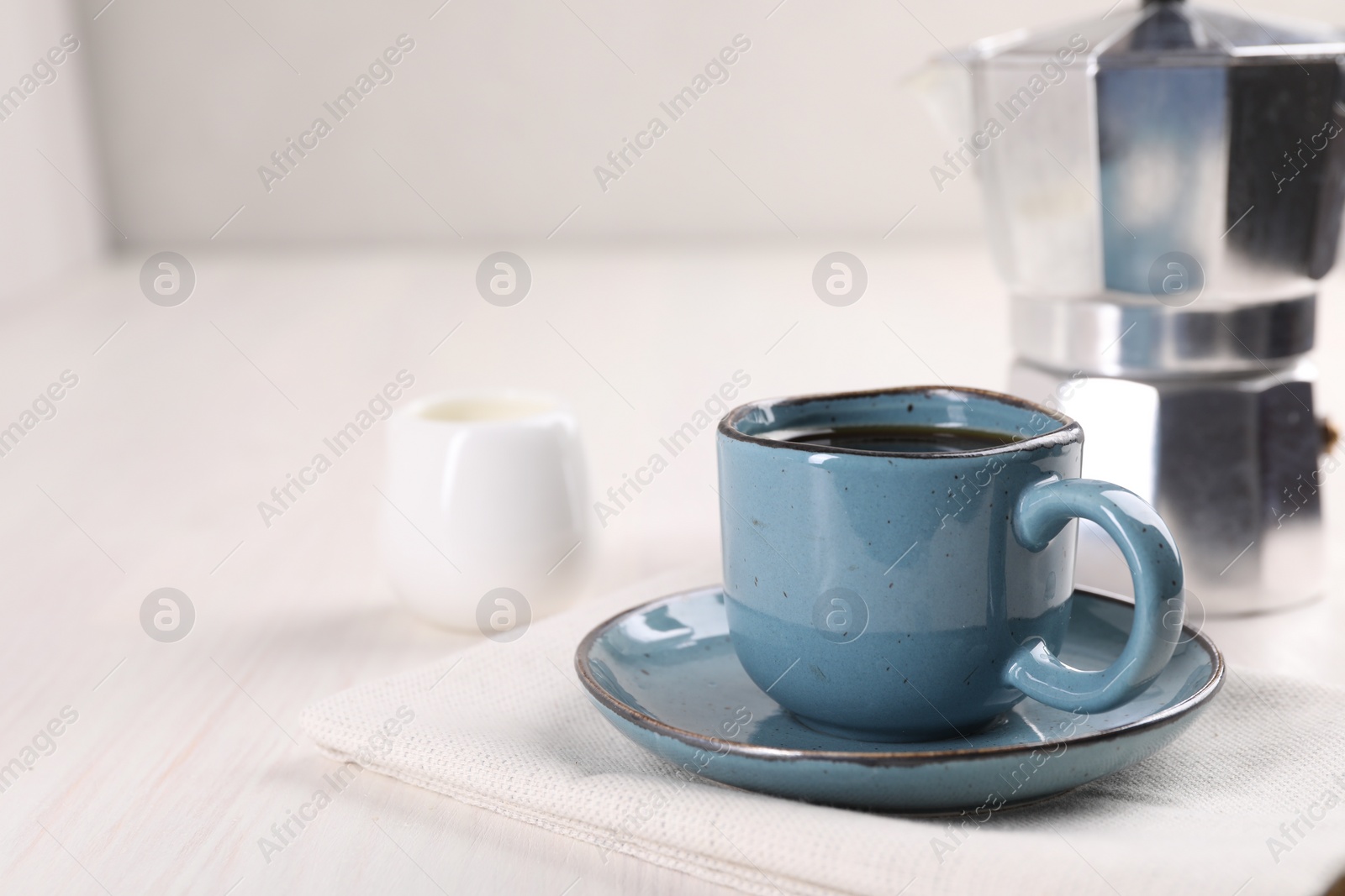 Photo of Delicious coffee in cup on white wooden table, closeup. Space for text