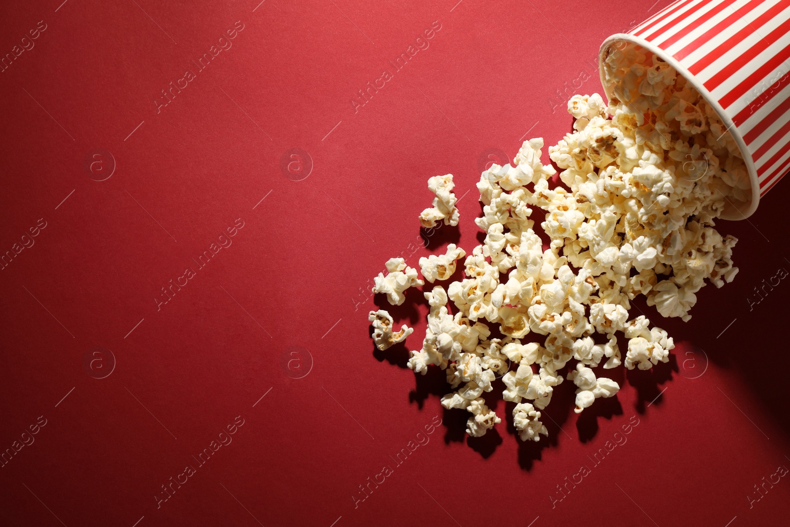 Photo of Delicious popcorn on red background, top view. Space for text