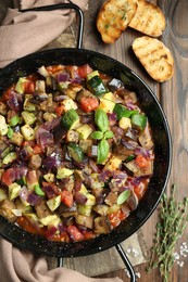 Delicious ratatouille in baking dish served on wooden table, flat lay