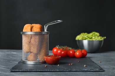 Photo of Slate plate with basket of cheese sticks and sauce on table. Space for text