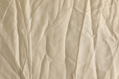 Photo of Crumpled beige fabric as background, top view