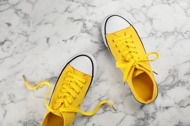 Pair of yellow sneakers on white marble table, flat lay