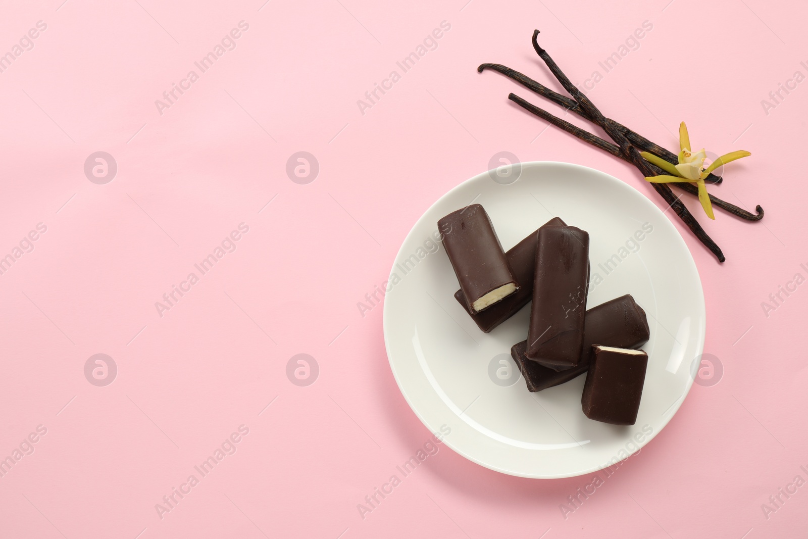 Photo of Glazed curd cheese bars, vanilla pods and flower on pink background, top view. Space for text