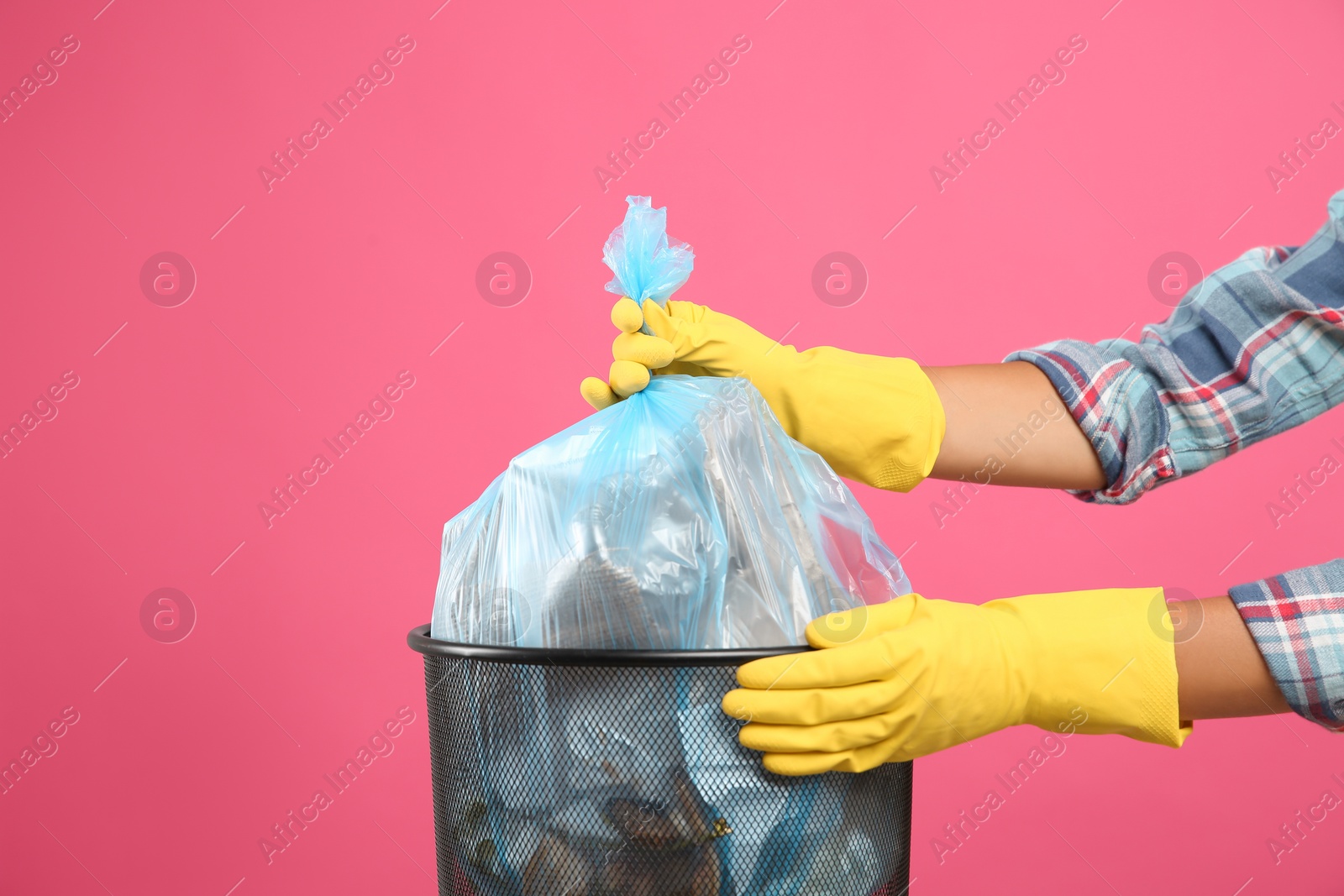 Photo of Woman taking garbage bag out of bin on pink background, closeup