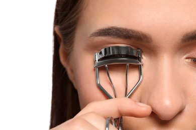 Woman using eyelash curler on white background, closeup