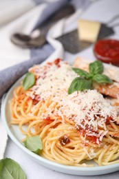 Delicious pasta with tomato sauce, basil and parmesan cheese on white table, closeup