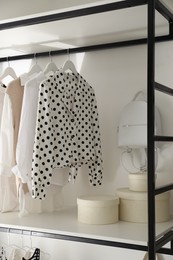 Photo of Storage rack with stylish women's clothes and accessories indoors