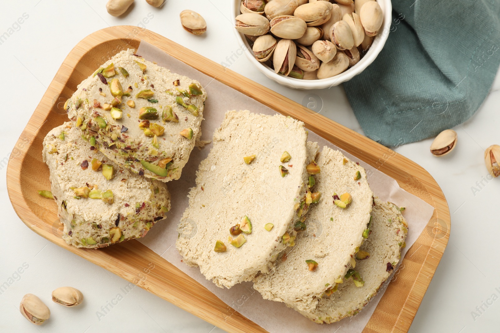 Photo of Tasty halva with pistachios on white table, top view