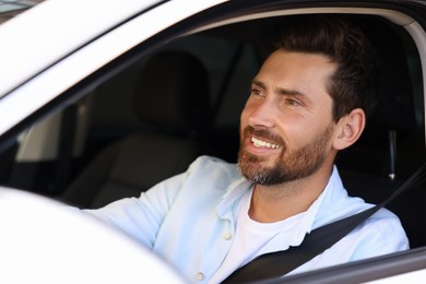 Photo of Enjoying trip. Handsome bearded man driving his car, view from outside