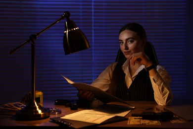 Professional detective working with documents in office at night