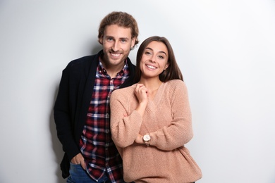 Young woman in warm sweater and man wearing knitted cardigan on white background