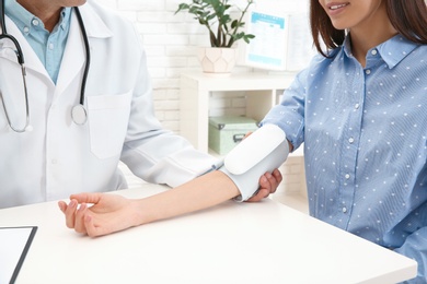 Photo of Doctor checking young woman's pulse with medical device in hospital, closeup