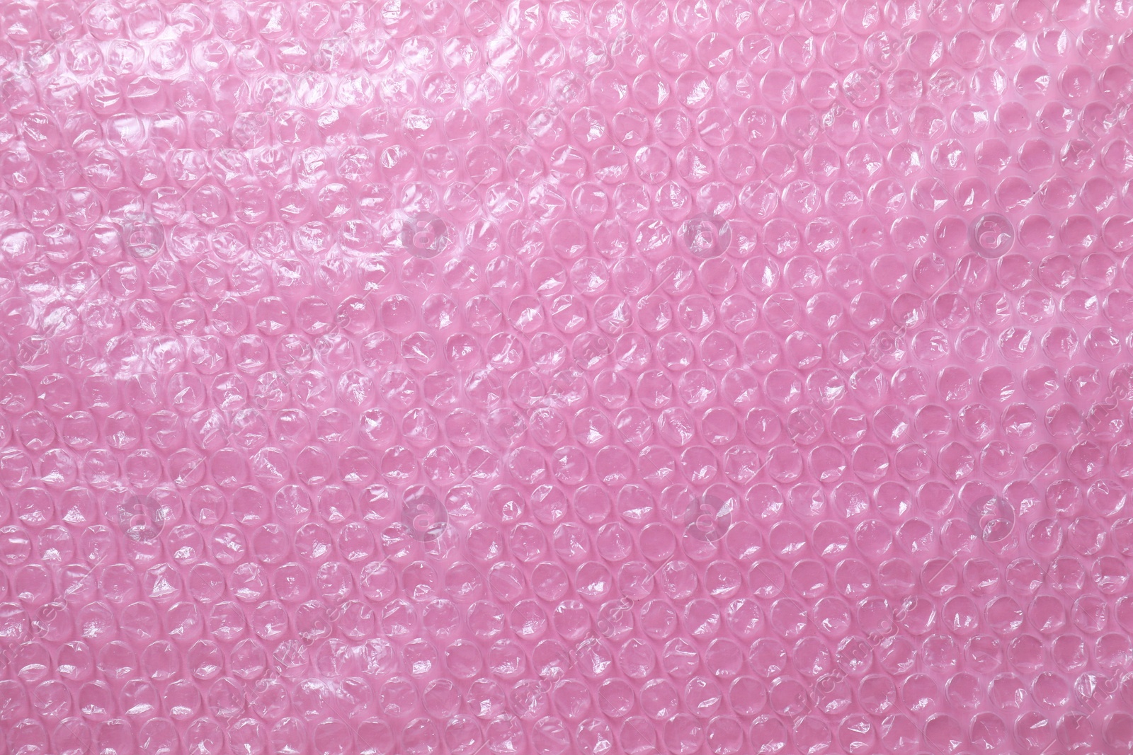 Photo of Transparent bubble wrap on pink background, top view