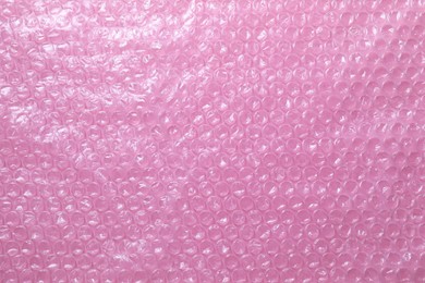 Photo of Transparent bubble wrap on pink background, top view