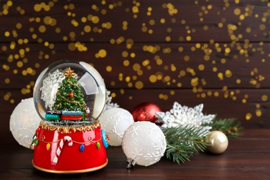 Beautiful Christmas snow globe and festive decor on wooden table. Space for text