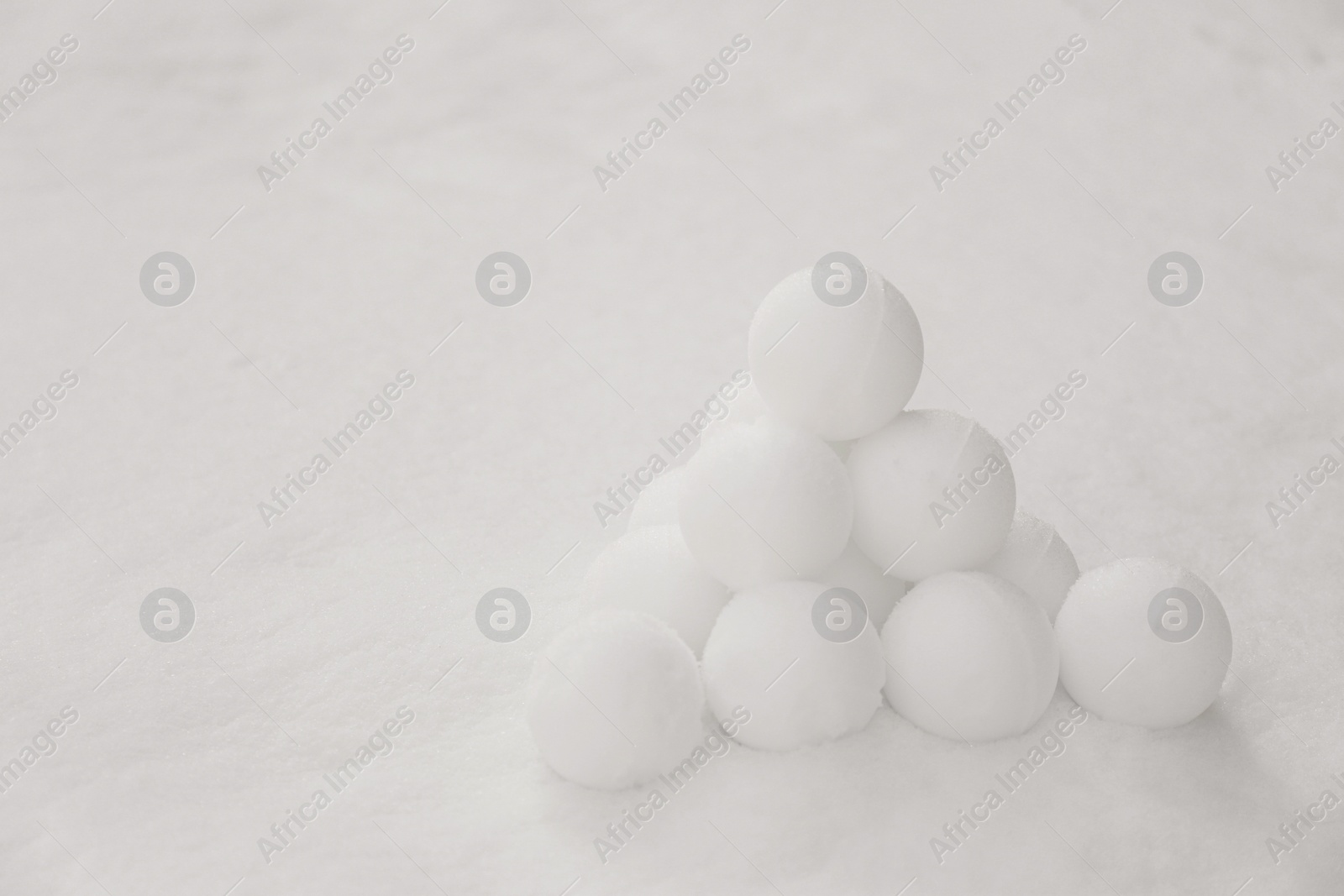 Photo of Pyramid of perfect snowballs on snow outdoors. Space for text