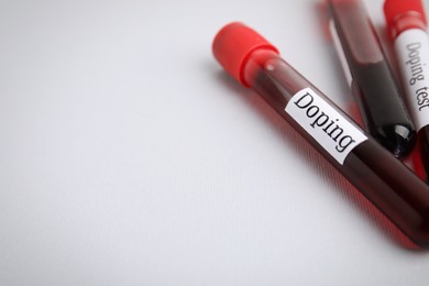 Photo of Closeup view of test tubes with blood samples on light grey background, space for text. Doping control