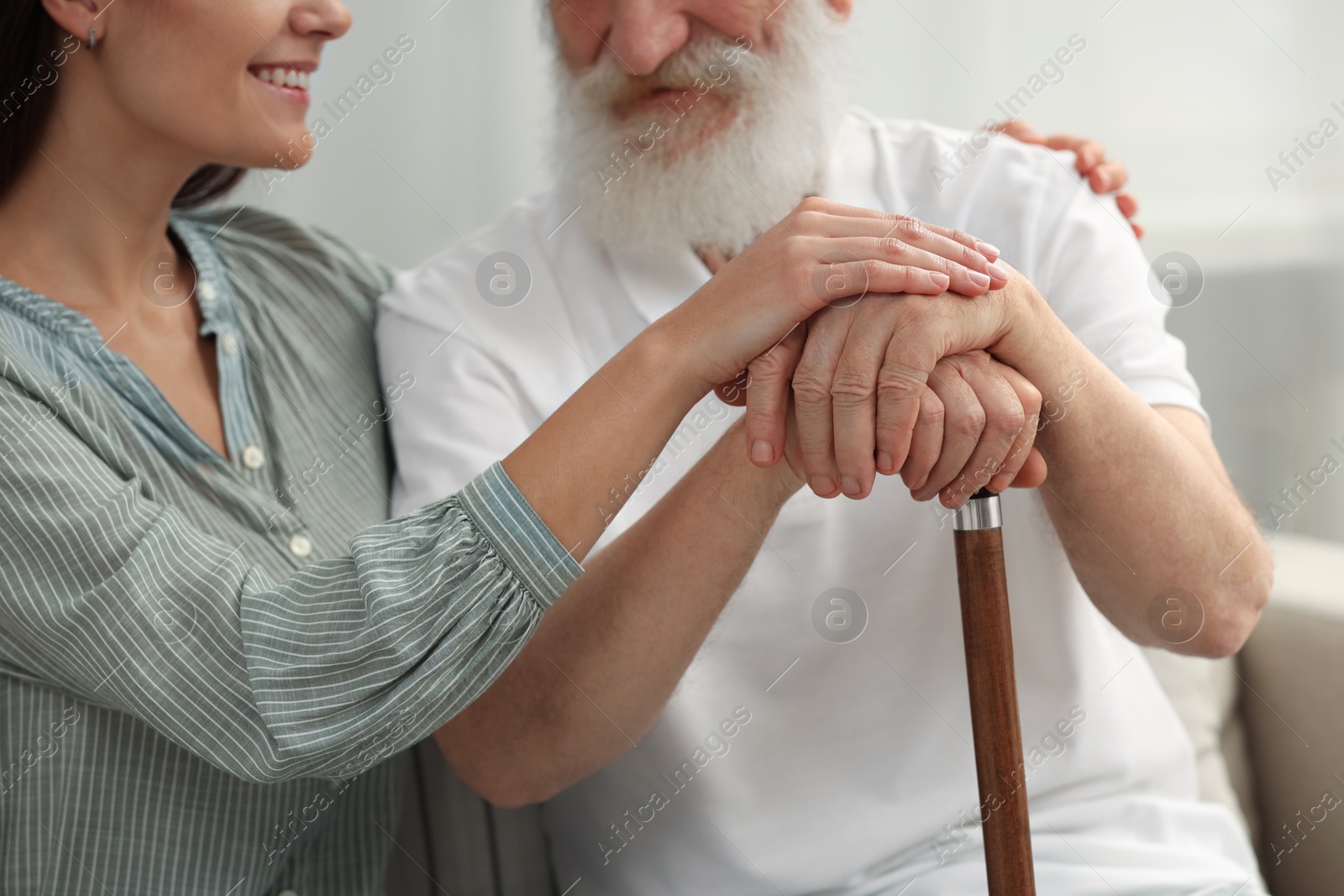 Photo of Senior man with walking cane and young woman indoors, closeup