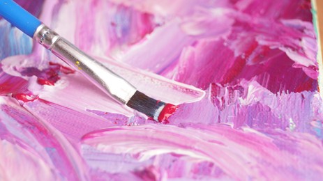 Photo of Applying colorful oil paints with brush on canvas, closeup