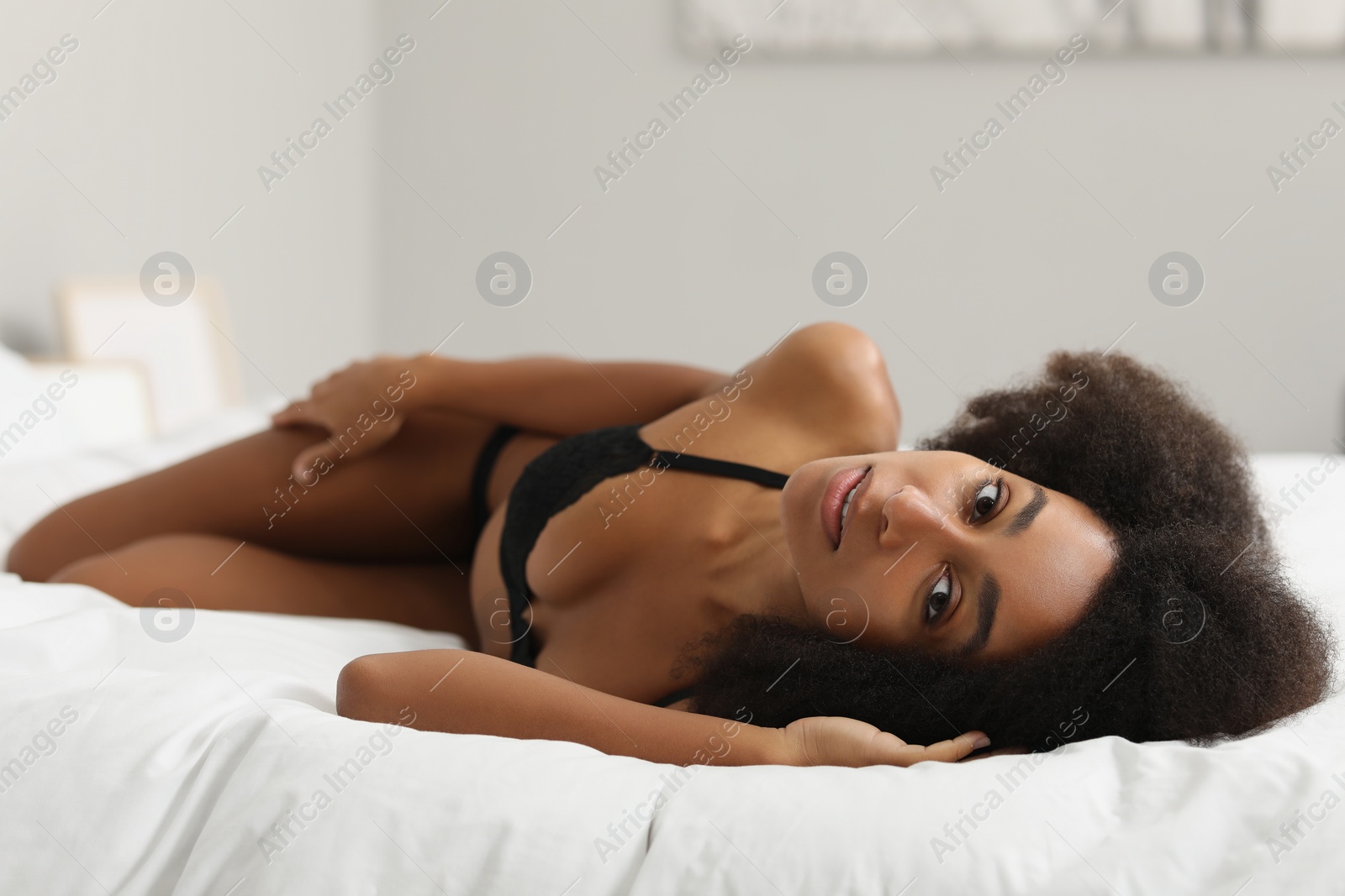 Photo of Beautiful woman in elegant black underwear on bed indoors