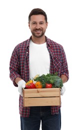 Photo of Harvesting season. Happy farmer holding wooden crate with vegetables on white background