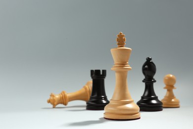 Photo of Different chess pieces against light background, focus on white king. Space for text
