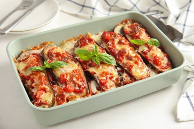 Photo of Baked eggplant with tomatoes, cheese and basil in dishware on white wooden table