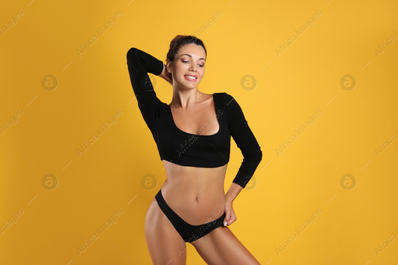 Photo of Beautiful woman in black sexy panties on yellow background