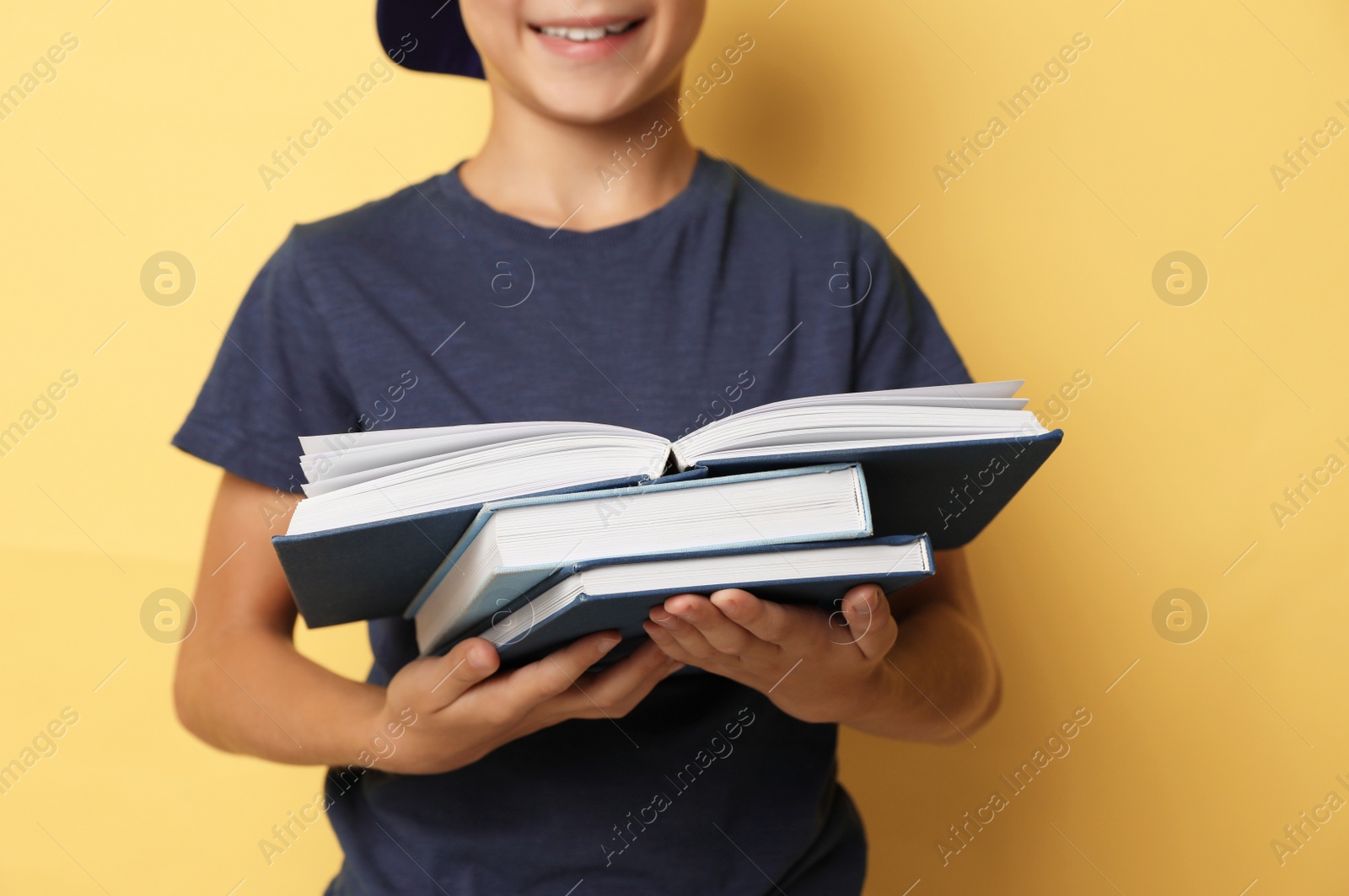 Photo of Little boy reading book on yellow background, closeup