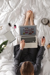 Photo of Woman and laptop with beauty blogger site on bed, top view