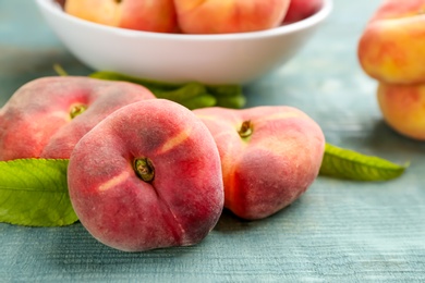 Photo of Fresh ripe donut peaches on light blue wooden table, closeup