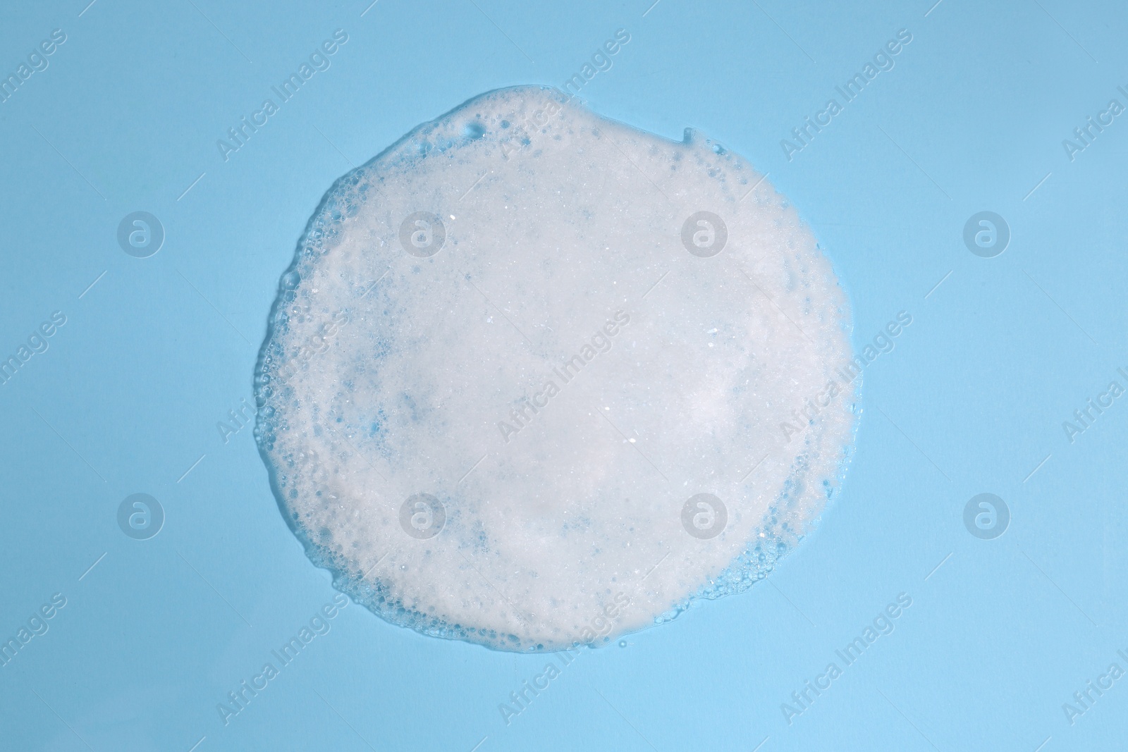 Photo of Foaming cleanser on light blue background, above view. Skin care cosmetic