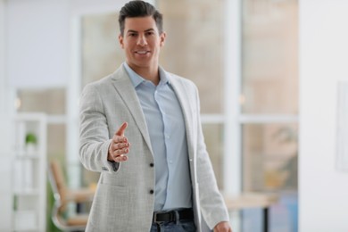Photo of Businessman reaching out for handshake in office, focus on hand