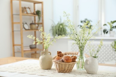 Photo of Fresh pastries and beautiful flowers on table in stylish dining room