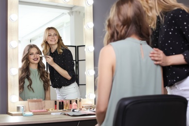 Photo of Professional makeup artist working with client in dressing room