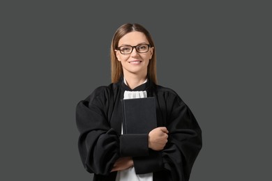 Portrait of smiling judge with book on grey background