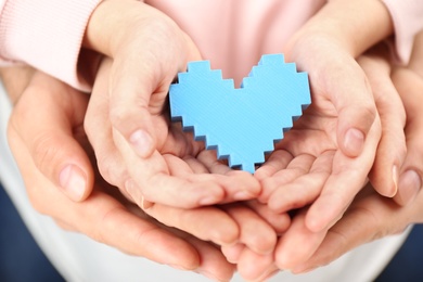 Photo of Parents and kid holding blue heart in hands, closeup. Family day